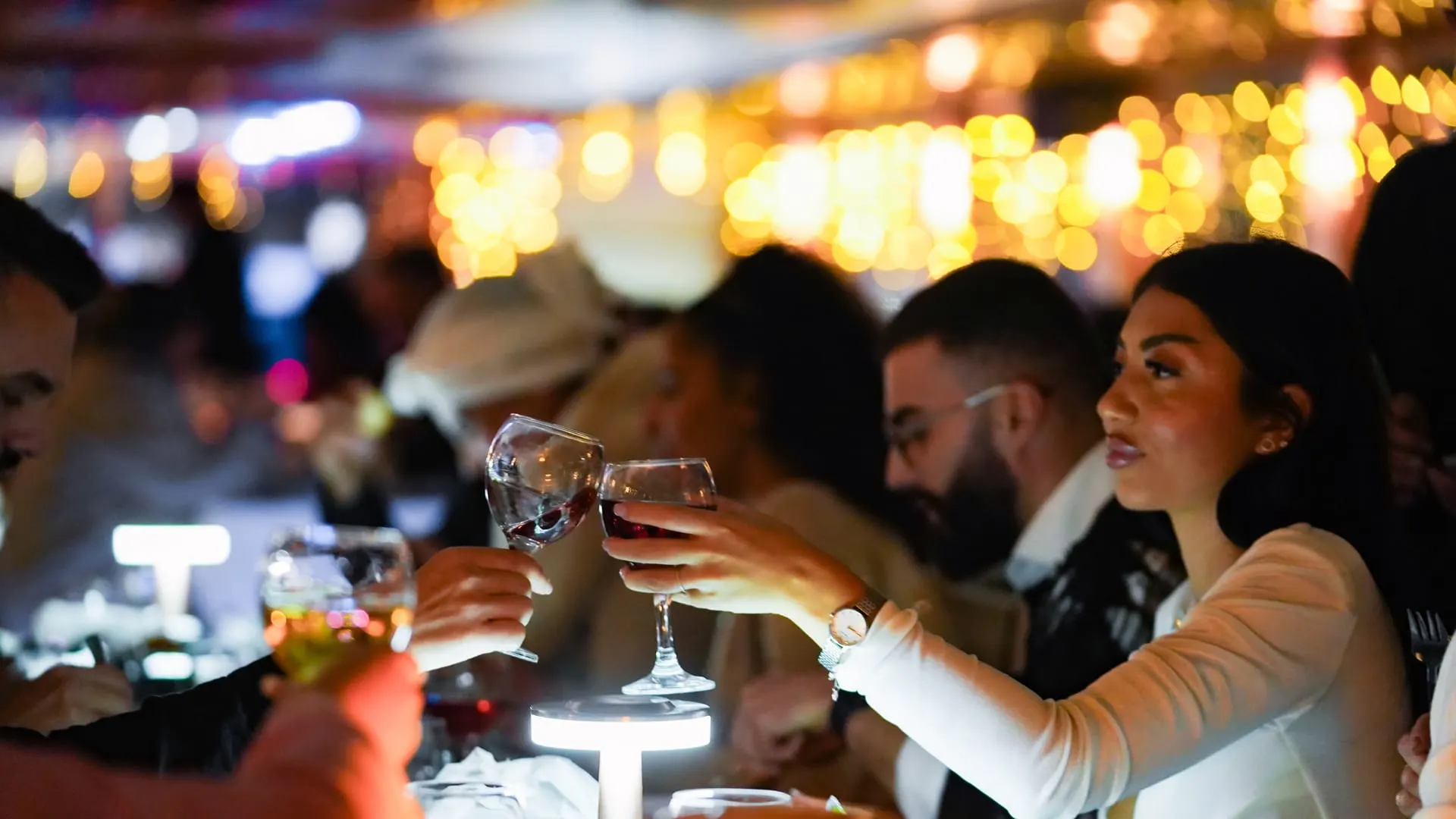 Guests raising glasses at a candlelit table on a Bosphorus night cruise